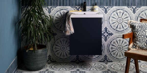 The wall features two types of tiles: a dark blue, possibly subway-style, tile on the upper part, and a patterned tile with a circular, almost mandala-like design in shades of blue and white on the lower half. This same patterned tile extends across the entire floor.