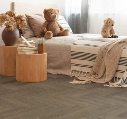 A child's bedroom with a neutral and warm aesthetic. The flooring is a dark, herringbone-patterned vinyl plank.