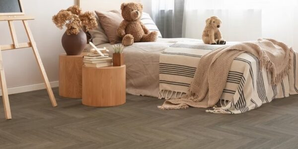 A child's bedroom with a neutral and warm aesthetic. The flooring is a dark, herringbone-patterned vinyl plank.