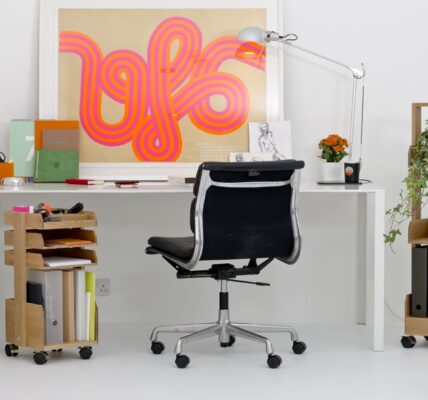 A brightly lit, modern home office space is shown. The room has white walls and a white floor, creating a minimalist backdrop for the furniture.