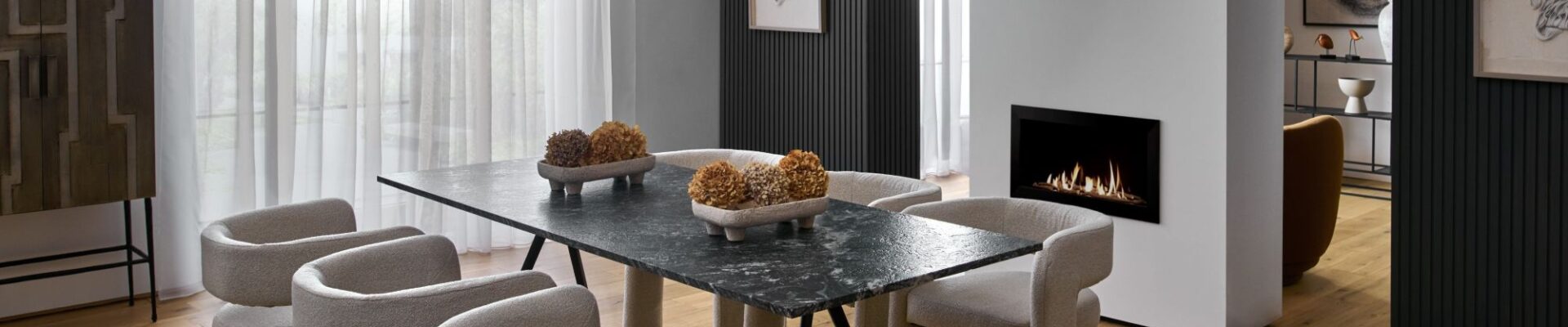 The flooring is a light-coloured wood, arranged in planks, which grounds the space and adds warmth. The room feels sophisticated and modern with a focus on clean lines, varied textures, and a neutral colour palette.