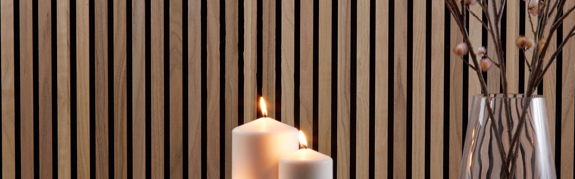 A close-up, horizontal image shows a cosy, homey interior scene. The background is a wall covered with vertical wooden slats in a warm, walnut tone.