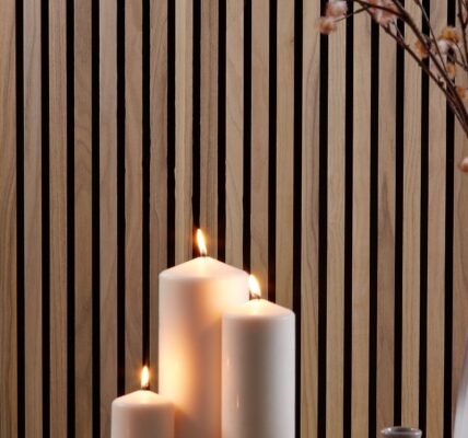 A close-up, horizontal image shows a cosy, homey interior scene. The background is a wall covered with vertical wooden slats in a warm, walnut tone.