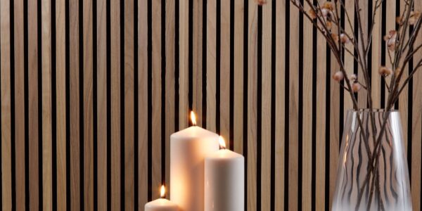 A close-up, horizontal image shows a cosy, homey interior scene. The background is a wall covered with vertical wooden slats in a warm, walnut tone.