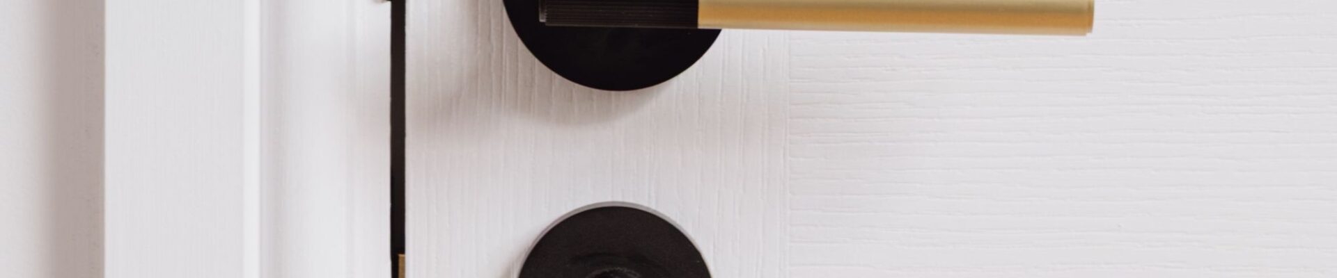 A linear lever handle with a modern, two-tone finish. It features a gold cylindrical main grip and a black or matte black accent on the end of the grip, which appears to have a subtle ribbed or textured surface. The handle is mounted on a round black rose