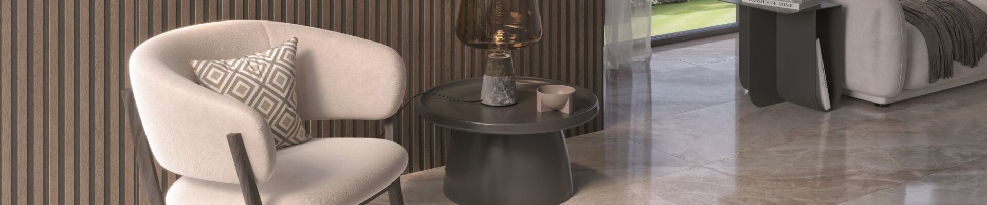 A luxurious, modern living space featuring a creamy white upholstered armchair, a ribbed wood accent wall, and glossy light-brown marble-look floor tiles. A dark round side table with a decorative lamp sits next to the chair, and a large window looks out onto a green garden.