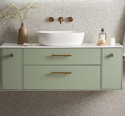 A wall-mounted vanity in a soft, muted sage green or light olive colour. It has two central drawers with long, horizontal brass or gold-tone handles.