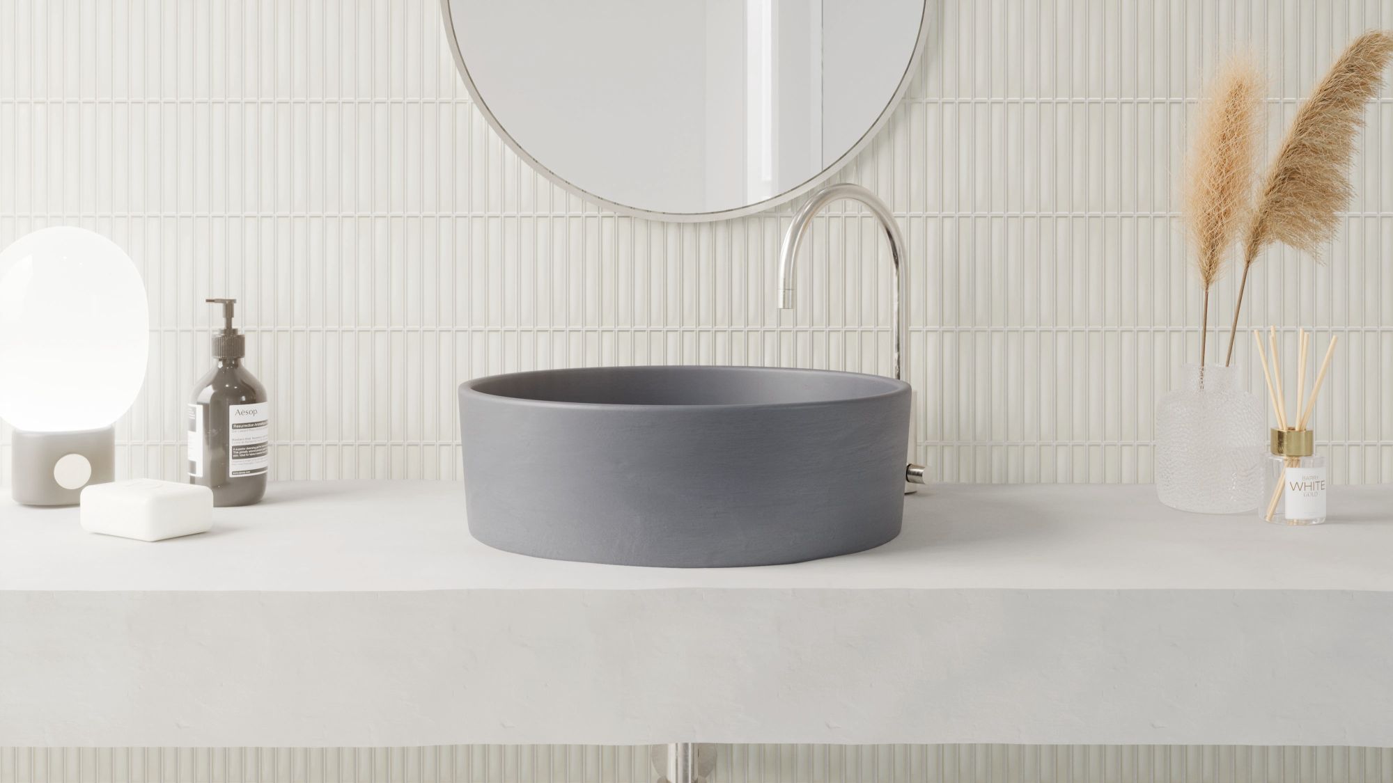 A modern bathroom vanity featuring a matte charcoal vessel sink on a concrete countertop against a white vertical Kit Kat finger tile backsplash.