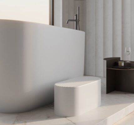 This image features a modern, luxurious bathroom with a large, freestanding white soaking tub positioned next to a window that offers a view of a city skyline at what appears to be sunrise or sunset.