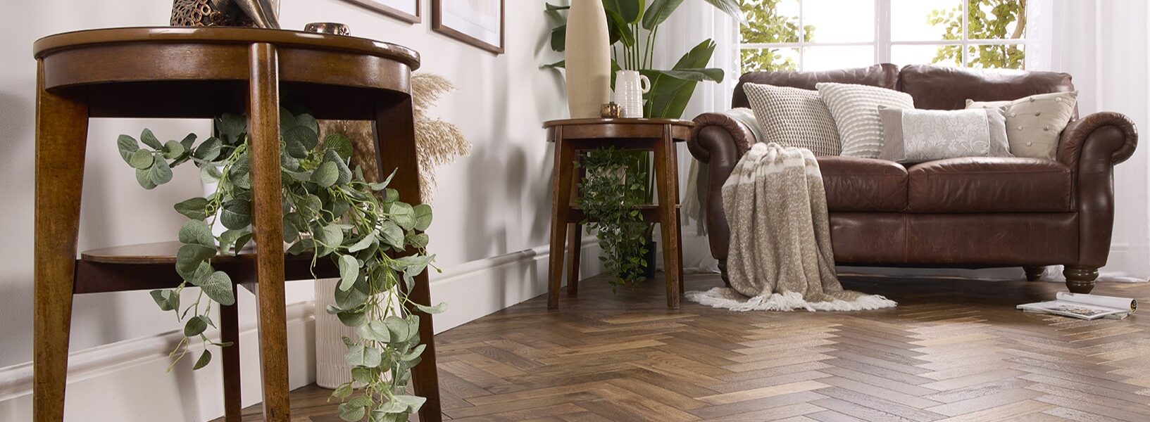 Alston Double Smoked herringbone engineered oak flooring in a brightly lit, modern living room with a brown leather sofa and wooden side tables