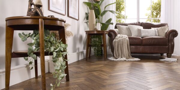 Alston Double Smoked herringbone engineered oak flooring in a brightly lit, modern living room with a brown leather sofa and wooden side tables