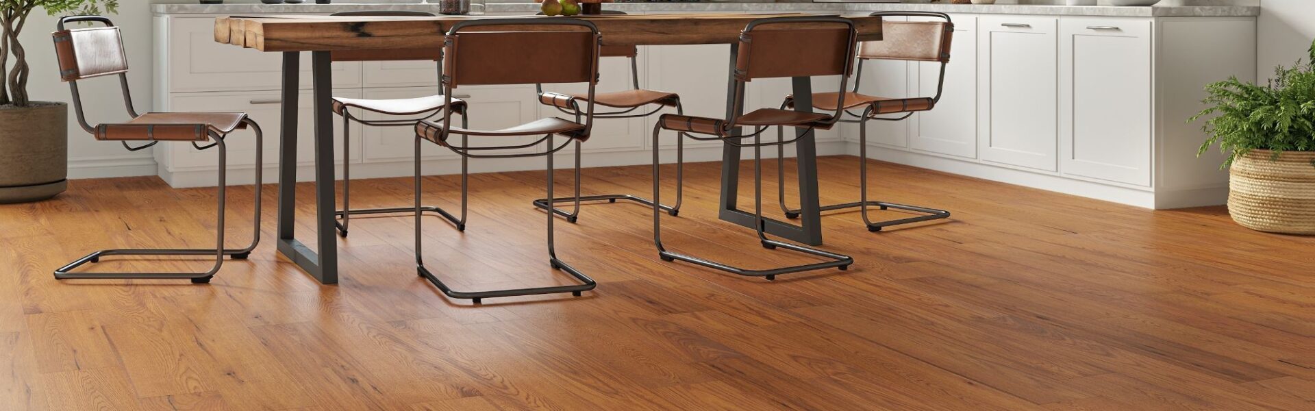 Golden-brushed UV oiled oak engineered wood flooring installed in a bright modern kitchen with a rustic dining table and white cabinets.