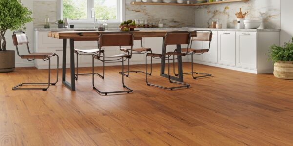 Golden-brushed UV oiled oak engineered wood flooring installed in a bright modern kitchen with a rustic dining table and white cabinets.
