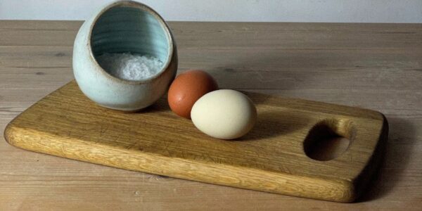 Eggs and a bowl of salt on a cutting board Description automatically generated