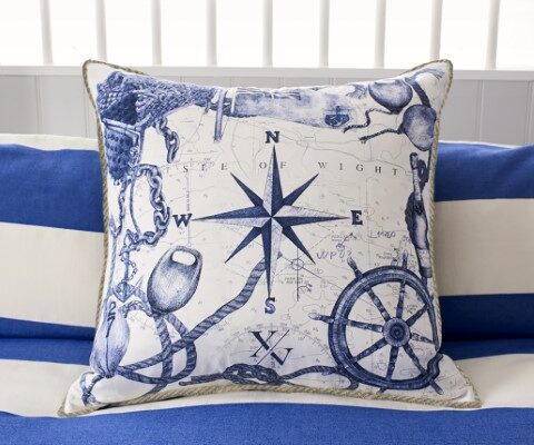 a coastal inspired cushion showing various marine symbols including a compass and a ship's wheel hand drawn in blue and white