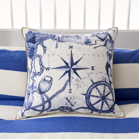 a coastal inspired cushion showing various marine symbols including a compass and a ship's wheel hand drawn in blue and white