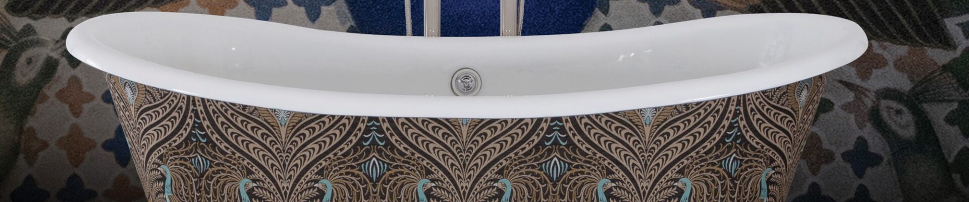 The image showcases a luxurious freestanding bathtub with a bold maximalist design, set against a similarly ornate background. The exterior of the tub is adorned with a peacock feather pattern, rendered in a palette of rich browns, golds, and teals. This intricate pattern gives the tub an opulent and bespoke appearance. The bathtub fixtures are traditional in style with a chrome finish, adding a touch of timeless elegance to the modern expression of maximalism. Behind the bathtub, a peacock-themed wall mural complements the tub's design, featuring an expanded tail in a display of vibrant green, blue, and gold hues, set against a deep blue background. The floor is a wooden texture, providing a warm, natural contrast to the cool tones of the tub and wall. The overall effect is one of lavishness and artistic flair, making a striking statement in this maximalist bathroom setting.