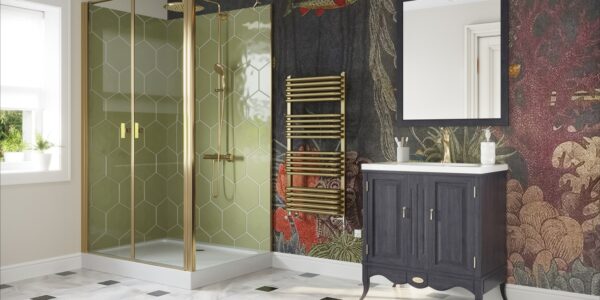 The image features a stylish bathroom with a contemporary design that incorporates brass elements. The focal point is a brushed brass dual fuel towel rail, which stands out against a dark, intricately patterned wallpaper that depicts a lush forest scene with hints of wildlife and florals in deep reds and greens. The shower enclosure showcases a geometric brass frame with clear glass, complementing the towel rail and adding a touch of modern luxury. The vanity unit is a classic dark wood with brass handles, contrasting the white basin above it and the white and black diamond patterned tile floor below. The space is well-lit, and there is a white-framed mirror above the vanity that reflects the natural light coming from the window. The overall aesthetic is one of elegance and warmth, with the brass accents lending a timeless yet trendy feel to the bathroom, exemplifying how brass fixtures can add sophistication to a home.
