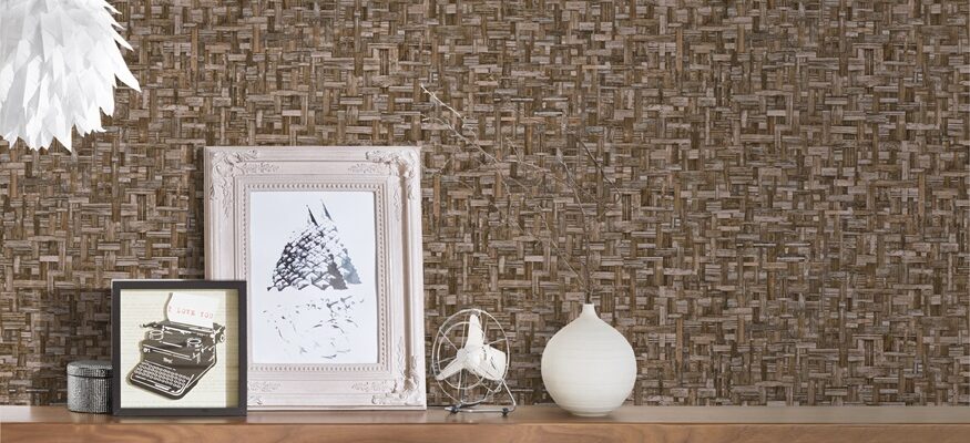 a wallpaper showing a woven effect. A shel;f onbthe wall holds some photographs and ornaments