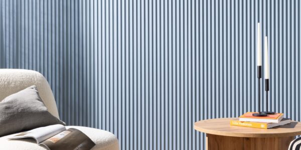 A living room with a wooden armchair, a round coffee table, and three lit candles on a tray.