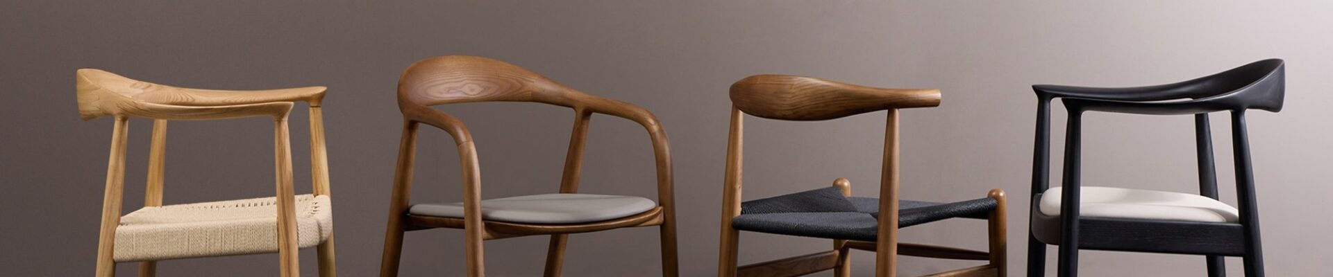 Four wooden chairs with brown upholstery in a row on a light wooden floor. The chairs are against a plain light wall.