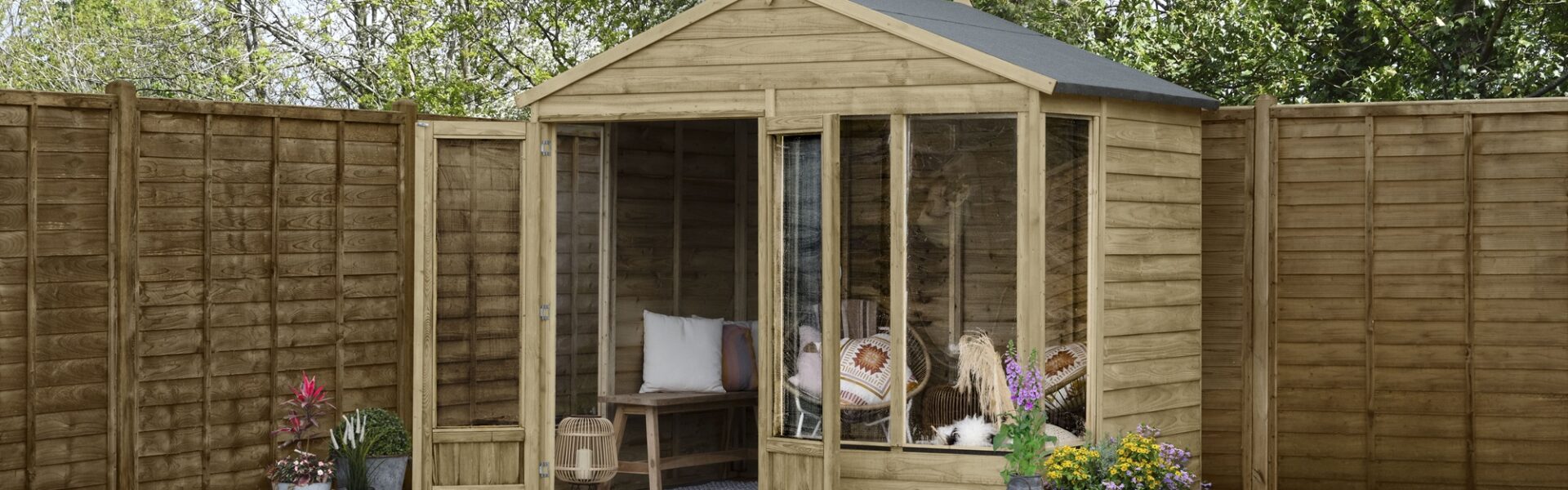 A brown wooden summerhouse is located in a garden. The shed has two doors and four windows. A wooden fence runs along the edge of the garden.
