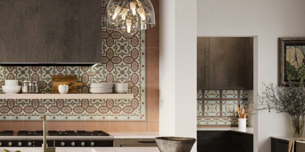 A kitchen with a stainless-steel stovetop oven and a black pendant light hanging from the ceiling. The countertop is a light-coloured stone with a mottled pattern. There are grey veined tiles on the wall behind the stovetop.