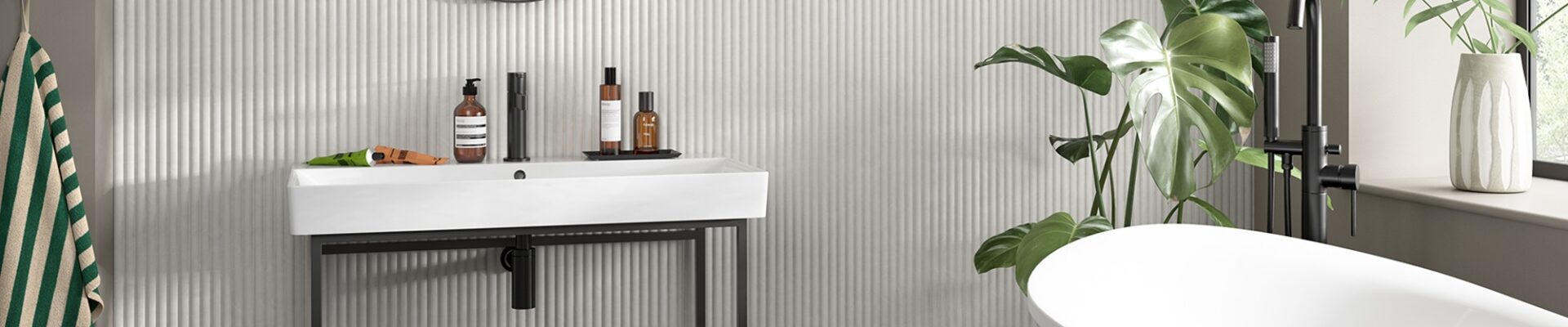 A small bathroom featuring modern reeded wooden wall-panelling with a white sink, mirror, and bathtub.