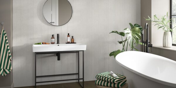 A small bathroom featuring modern reeded wooden wall-panelling with a white sink, mirror, and bathtub.