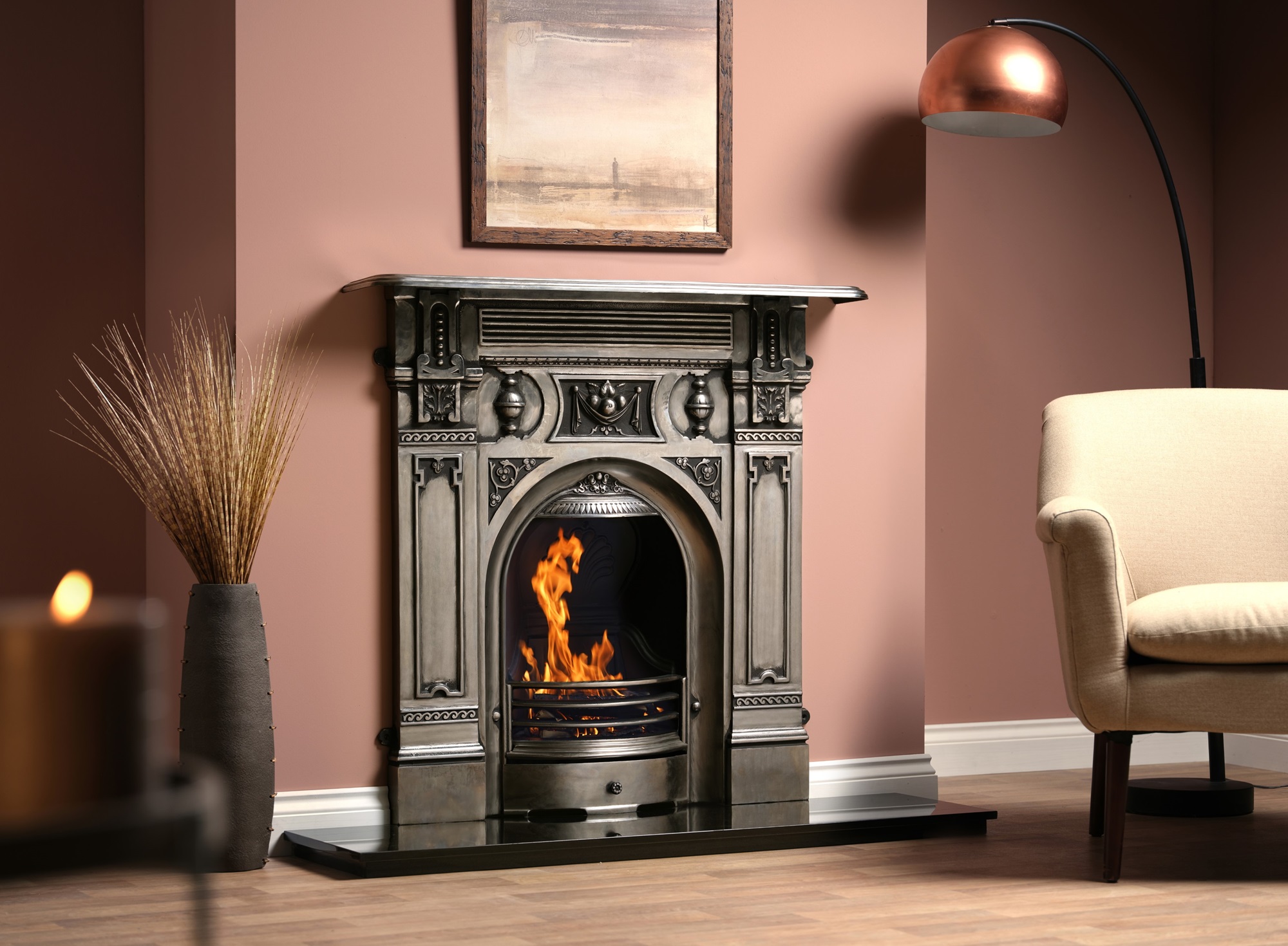 A cast iron fireplace with a fire burning in the grate. The fireplace is in a living room with an armchair next to it.