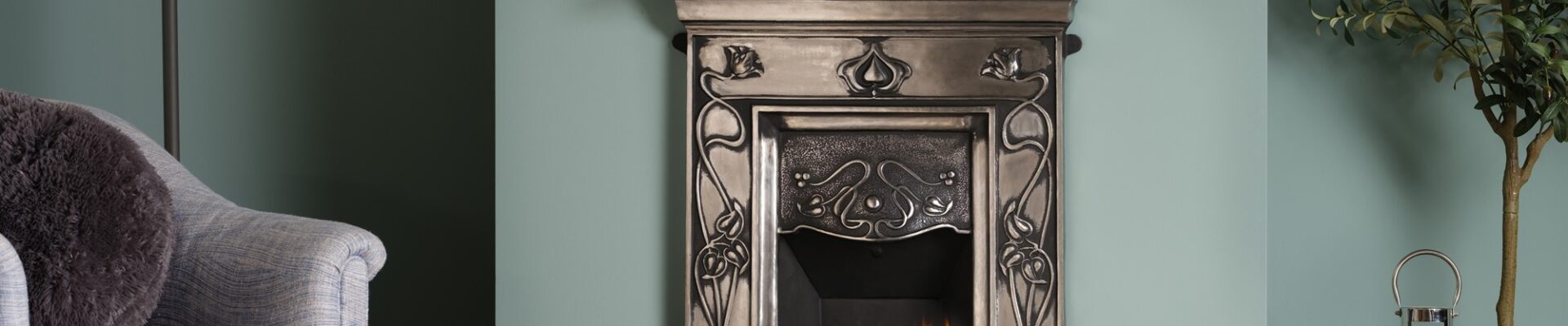 A cast iron fireplace with a fire burning in the grate. The fireplace is in a traditional living room setting, with an armchair next to it.