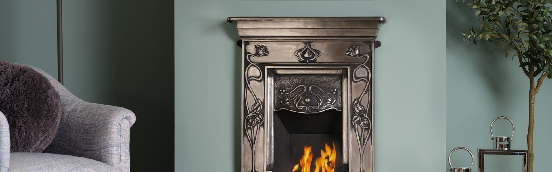 A cast iron fireplace with a fire burning in the grate. The fireplace is in a traditional living room setting, with an armchair next to it.