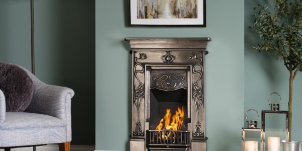 A cast iron fireplace with a fire burning in the grate. The fireplace is in a traditional living room setting, with an armchair next to it.