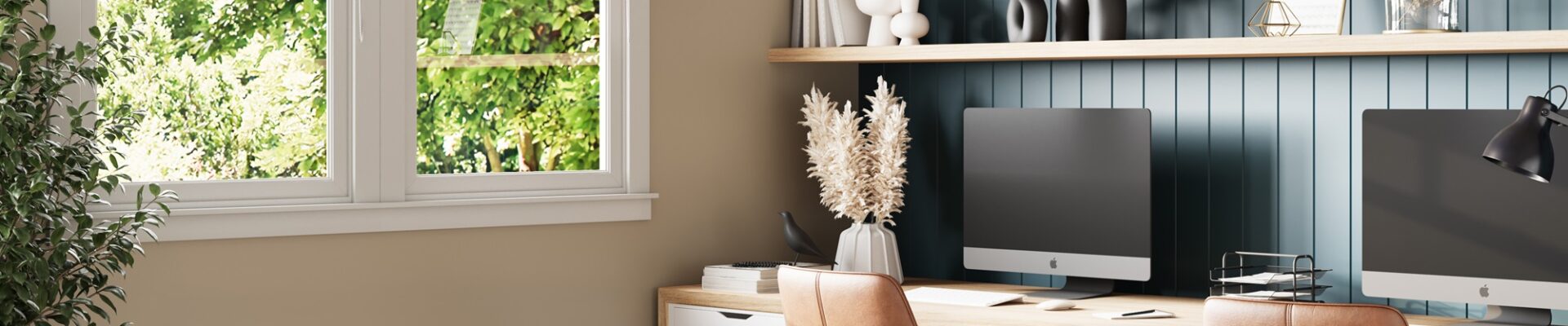 A home office with two desktop computers and two ergonomic chairs facing a window.