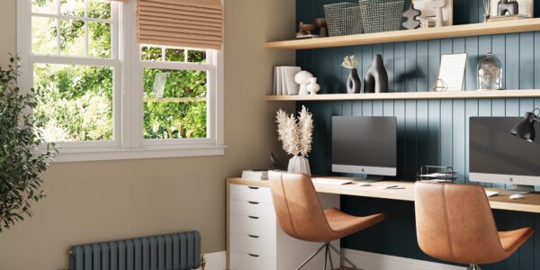 A home office with two desktop computers and two ergonomic chairs facing a window.