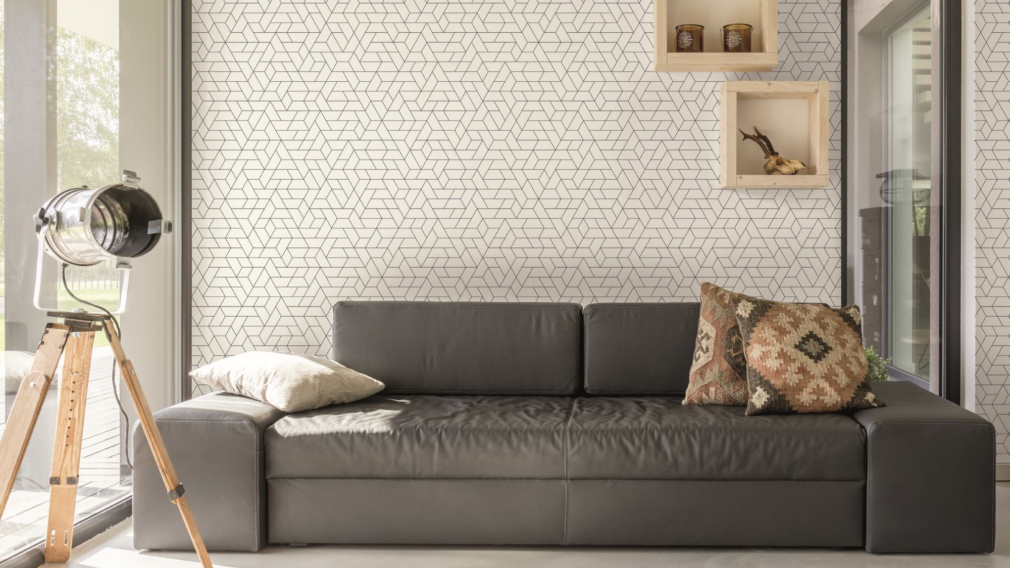 A cosy living room with a brown leather couch and a tall lamp with a white shade in front of a window.