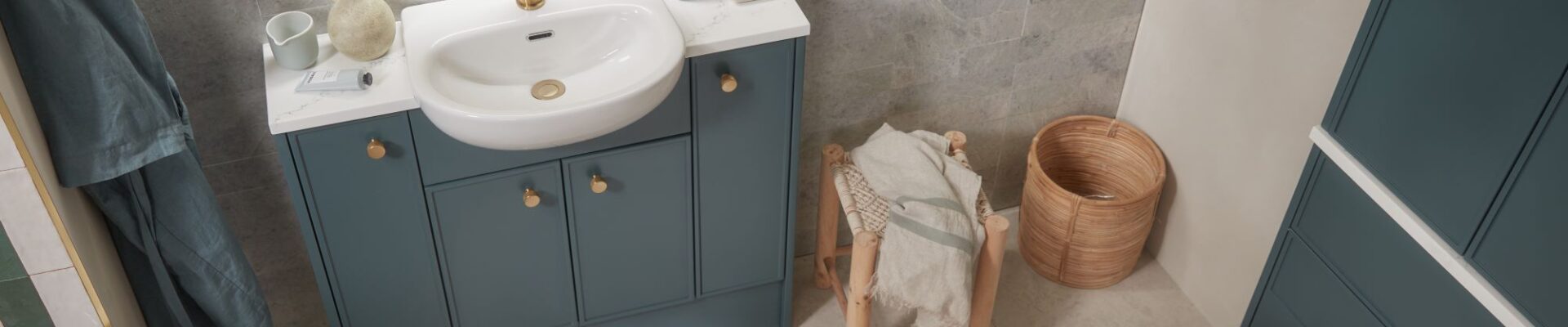 A white bathroom with a sink and toilet. The storage cupboards are a shade of forest green.