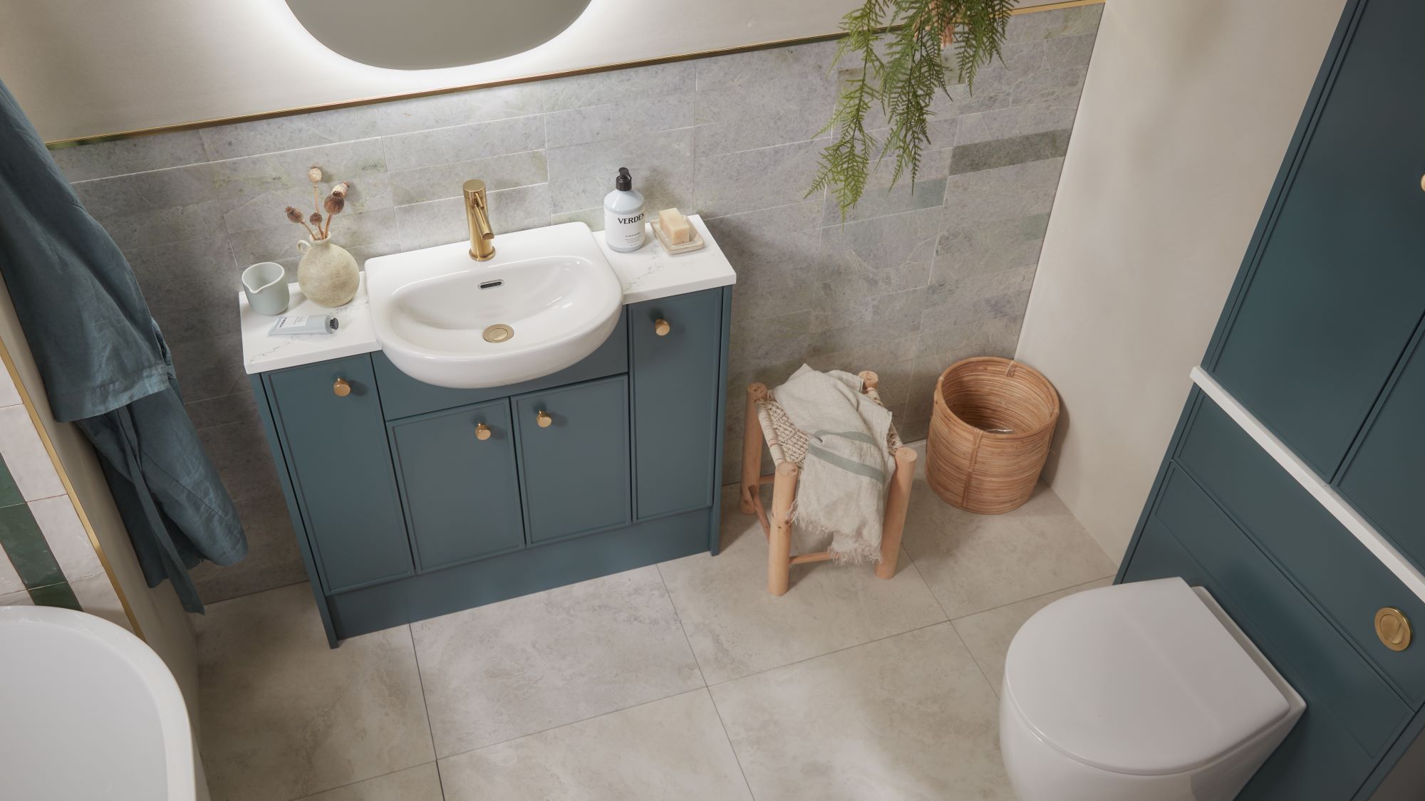 A white bathroom with a sink and toilet. The storage cupboards are a shade of forest green.