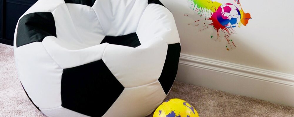 White soccer ball bean bag chair on floor next to soccer ball