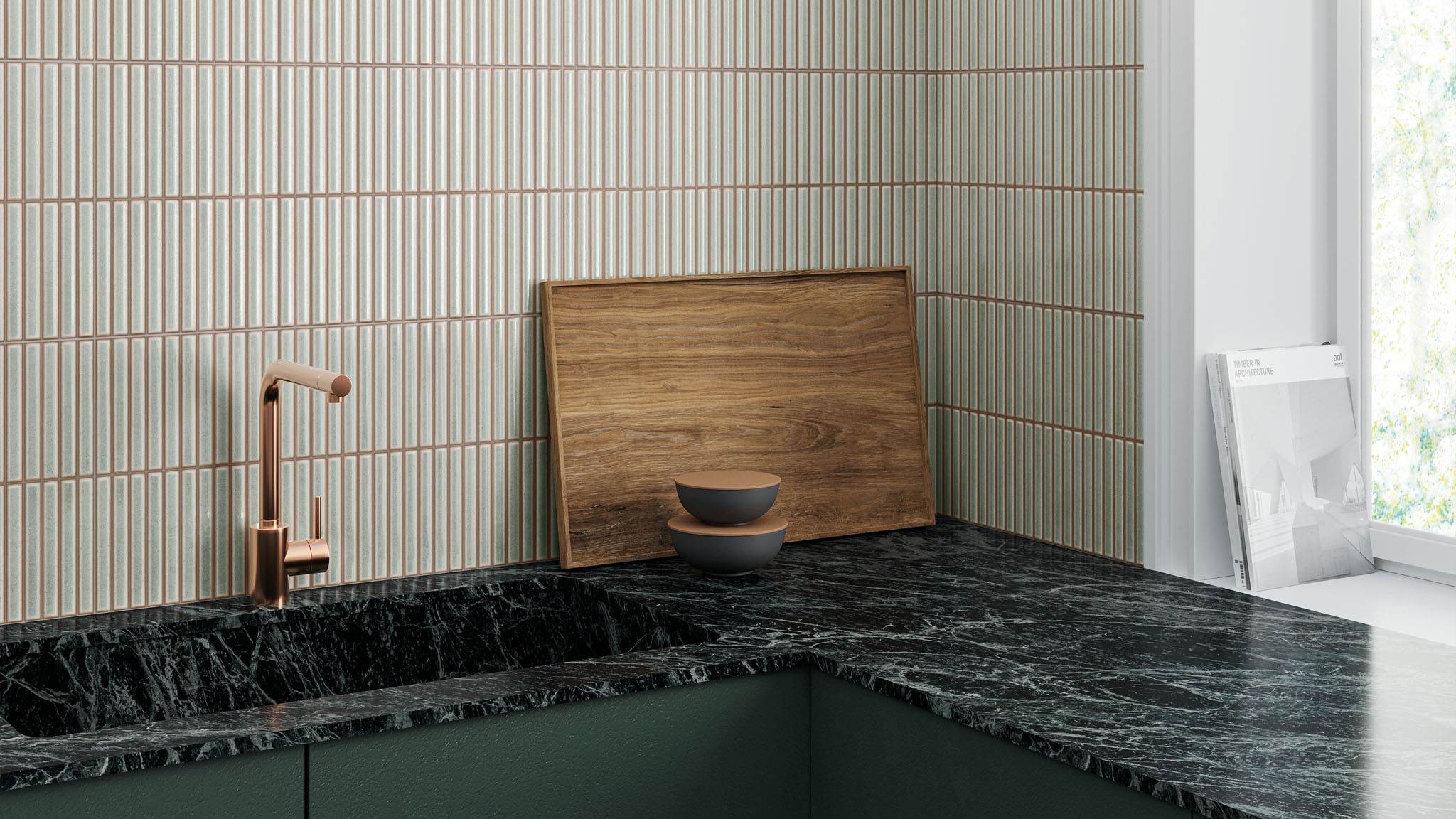 A kitchen countertop with a black marble worktop and a dark green cupboard below. A copper-coloured faucet is mounted on the countertop. There is a wooden cutting board and two bowls on the countertop. The wall behind the countertop is tiled with white tiles with vertical grooves.