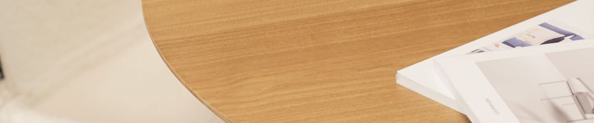 A wooden table with a circular design. This table is finished in a natural colour and is inspired by Scandinavian design