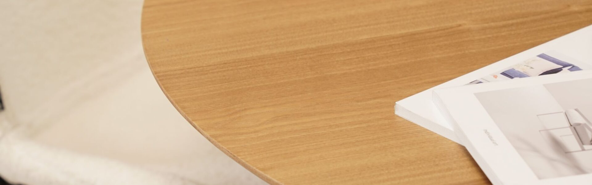 A wooden table with a circular design. This table is finished in a natural colour and is inspired by Scandinavian design