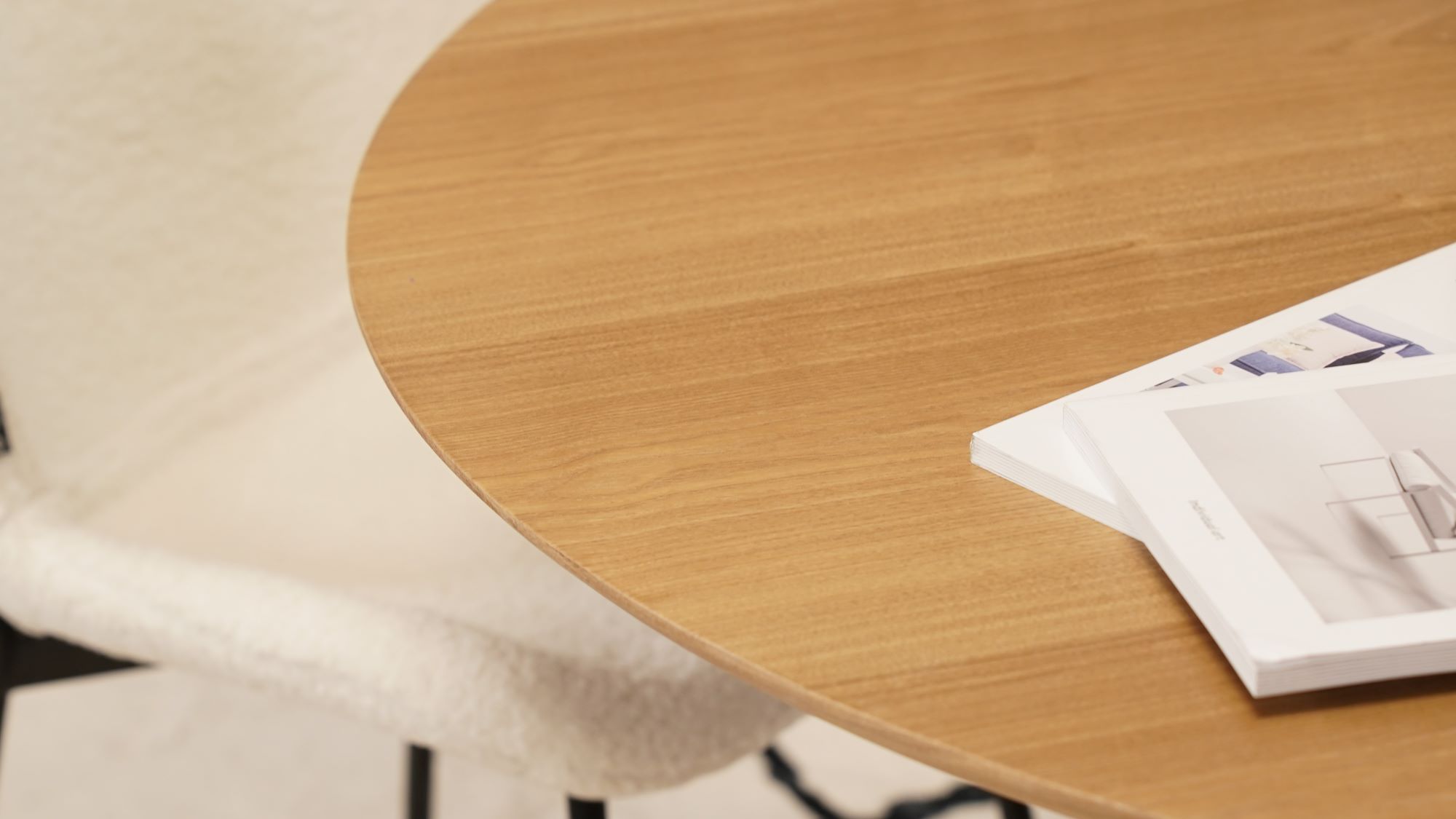 A wooden table with a circular design. This table is finished in a natural colour and is inspired by Scandinavian design