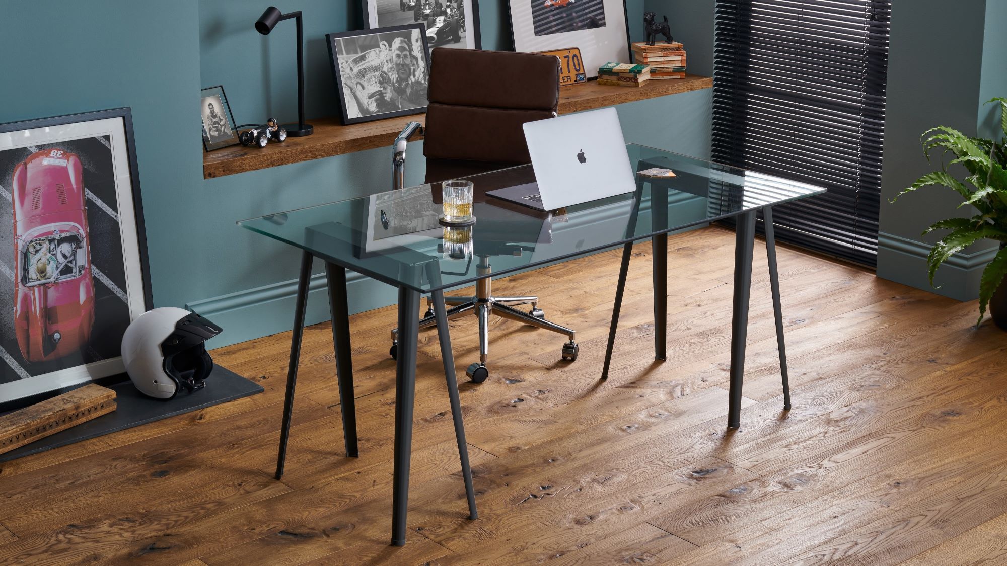 The image shows a modern home office space with dark wood floors and a glass desk.