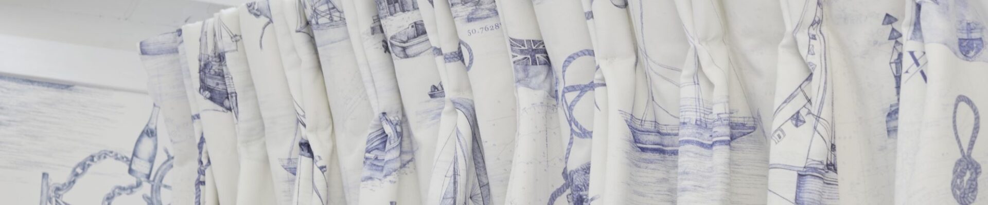 The curtains are white with a blue nautical pattern featuring boats, ships, and anchors. The rod is white and appears to be curved.