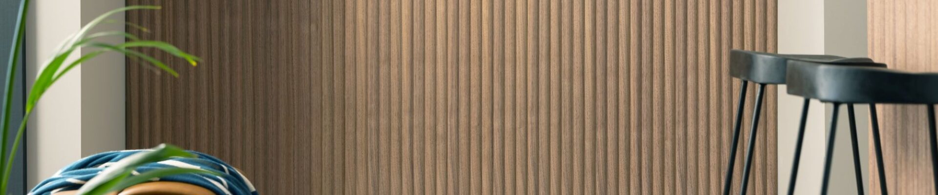 The wall is covered in a vertical wood-panelled design, adding a touch of warmth and texture to the space. The rest of the kitchen seems to be a neutral colour, with light grey countertops and a sleek white backsplash.