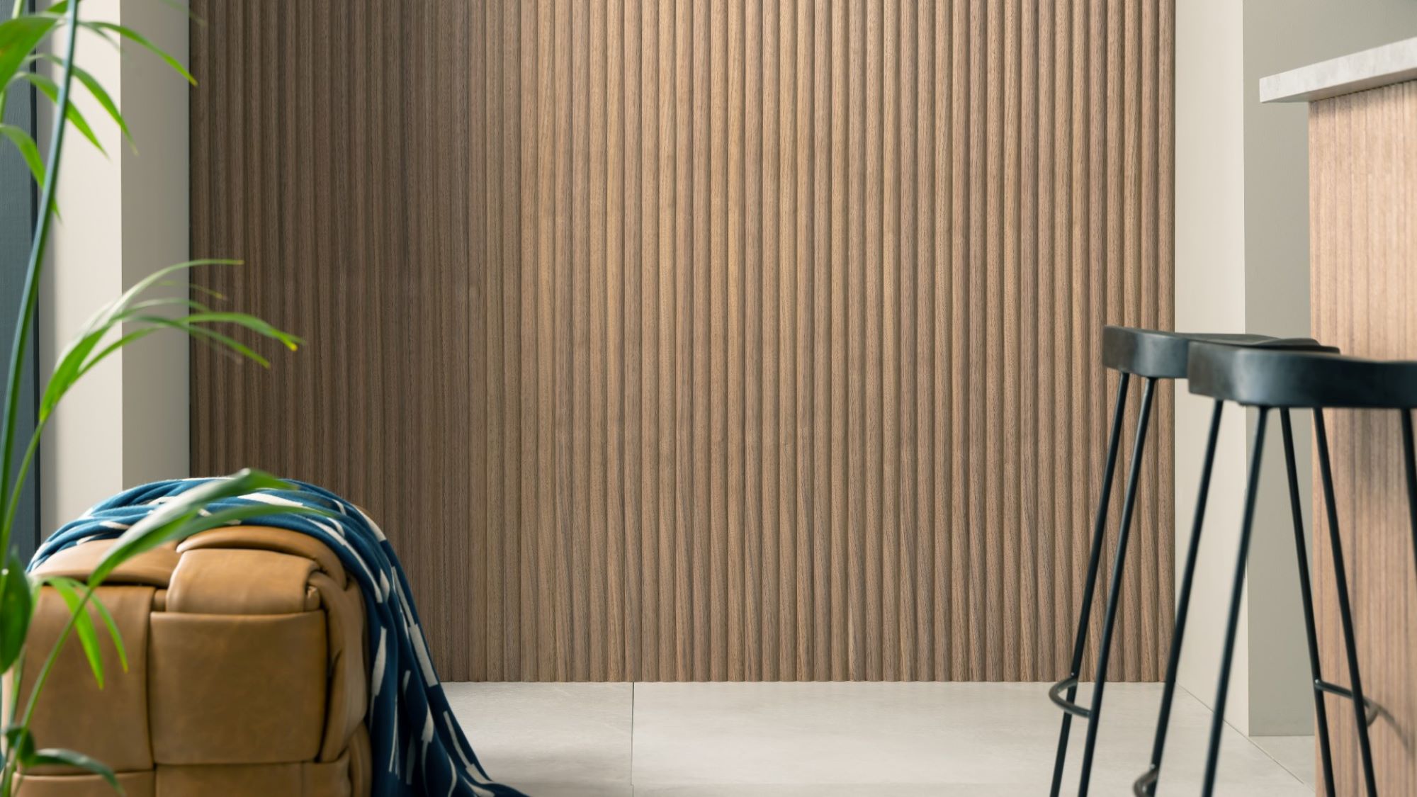 The wall is covered in a vertical wood-panelled design, adding a touch of warmth and texture to the space. The rest of the kitchen seems to be a neutral colour, with light grey countertops and a sleek white backsplash.