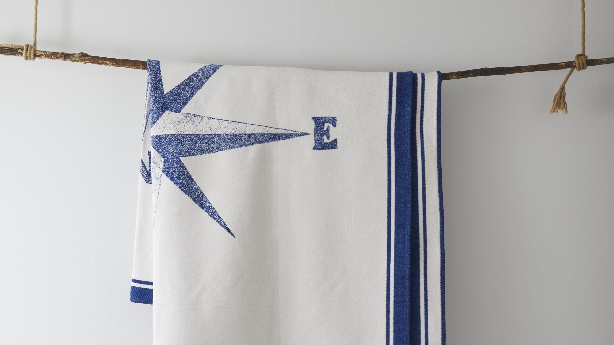 A white blanket with a nautical theme hangs from a branch.