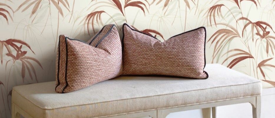 The image creates a serene and inviting atmosphere. The light colours and natural elements of the wallpaper and pillows give a sense of calm and relaxation. The simple design of the bench adds to the overall minimalist aesthetic.