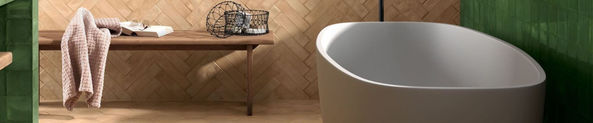 Modern bathroom with a freestanding white tub and a herringbone terracotta tile wall.